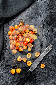 Mix of yellow and red ripe cherries. Black background. Top view