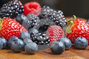 Mixed berries on wooden background with selected focus