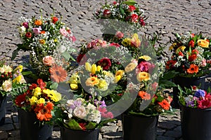 Mixed bunches of spring flowers in basket outdoors, bouquet of different flowers selling in a market on paving stones