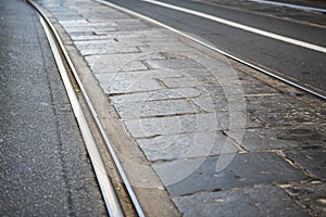 Mixed cobbles pavÃ¨ and tarmac city road with tramway tracks in Turin