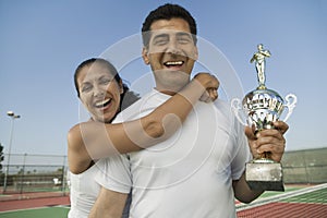 Mixed doubles Tennis Players standing in tennis court holding trophy portrait