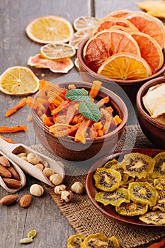 Mixed dried fruit chips, candied pumpkin slices, nuts and seeds on rustic wooden background