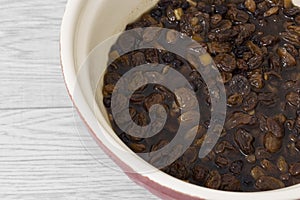 Mixed dried fruit soaking in a tea marinade in a mixing bowl.