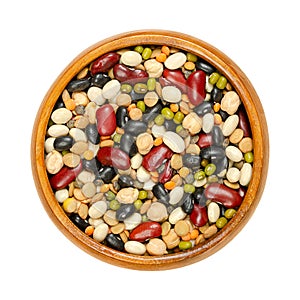 Mixed dried pulses in a wooden bowl, from above, isolated, over white