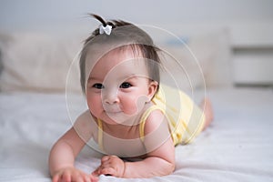 mixed ethnicity Asian Caucasian baby girl crawling on bed happy and curious - sweet and adorable little baby 8 months old with a