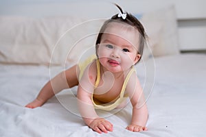 mixed ethnicity Asian Caucasian baby girl crawling on bed happy and curious - sweet and adorable little baby 8 months old with a