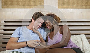 Mixed ethnicity couple in love cuddling together at home in bed with beautiful playful black afro American woman and caucasian