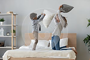 Mixed ethnicity mum and son enjoy pillow fight on bed