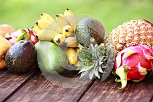 Mixed exotic fruits on wood background. Healthy eating, dieting. Top view with grass copy space