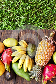 Mixed exotic fruits on wood background. Healthy eating, dieting. Top view with grass copy space