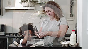 Mixed family baking - mom breaks an egg into a glass bowl for the dough