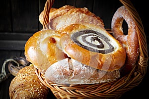 Mixed of fresh baked breads and buns in a basket on dark background