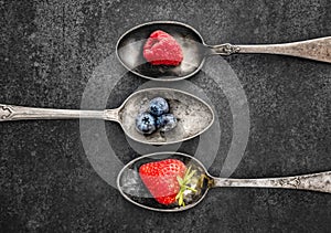 Mixed fresh berries laying in three separated spoons