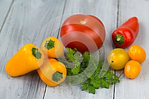 Mixed fresh colored vegetables, cherry tomatoes, mini paprika, tomato and fresh herbs on a wooden background