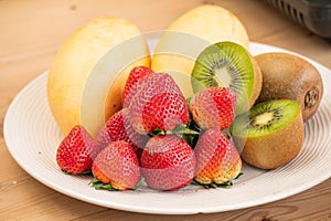 Mixed fresh fruits strawberry, raspberry, blueberry, kiwi, mango on wood bowl