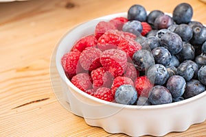 Mixed fresh fruits strawberry, raspberry, blueberry, kiwi, mango on wood bowl