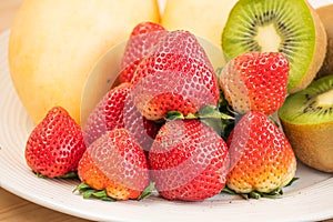 Mixed fresh fruits strawberry, raspberry, blueberry, kiwi, mango on wood bowl