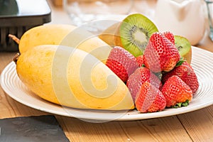 Mixed fresh fruits strawberry, raspberry, blueberry, kiwi, mango on wood bowl