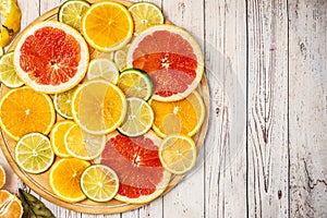 Mixed Fresh slices citrus fruit on a round wooden Board on a light background. Top view. With copy space