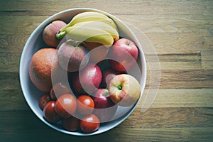 Mixed fruit bowl on wood background