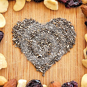 Mixed fruits,nuts, and chia seed heart on wood grain cutting board, arranged in square for social media, banners, and backgrounds.