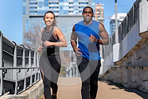 Mixed gender group running outdoors in urban city, man and woman couple, exercising fitness on sunny day