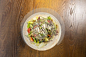 Mixed green salad with shaved parmesan cheese served on wooden table