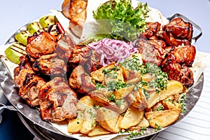 Mixed grill meat fried vegetables and grilled salmon fish fillets decoration in warm dish. Assorted delicious grilled kebab served