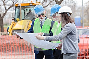 Mixed group of architects and business partners discussing project details on a construction site