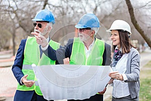 Mixed group of architects and business partners discussing project details during inspection of a construction site