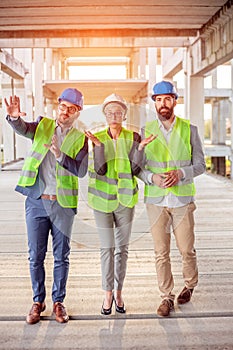 Mixed group of architects walking through prefabricated concrete construction site, inspecting work progress