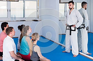 Mixed group of trainees listens to the karate coach