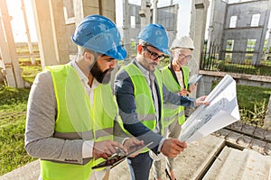 Mixed group of young architects and civil engineers or business partners meeting on a large construction site photo