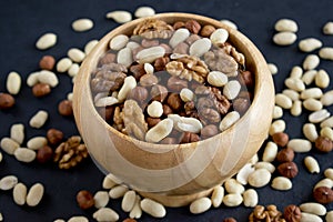 Hazelnuts, peanuts, walnuts in wooden bowl on black background