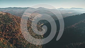 Mixed hilly forests lit by sunlight against pictorial hills