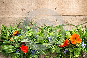 Mixed Leaves and Edible Flowers on Light Wooden Background