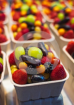 Mixed many type of fruits and berries in the paper box at the marketplace or superstore. Fruit salad in takeaway cup