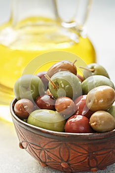 Mixed marinated olives green, black and purple in ceramic bowl and olive oil