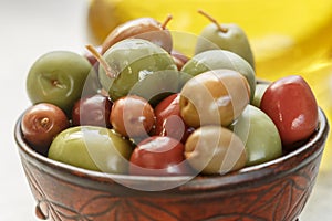 Mixed marinated olives green, black and purple in ceramic bowl and olive oil