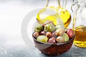 Mixed marinated olives green, black and purple in ceramic bowl and olive oil