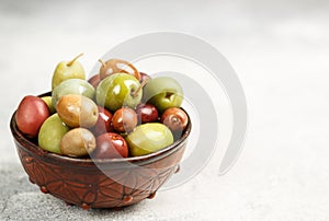 Mixed marinated olives green, black and purple in ceramic bowl and olive oil