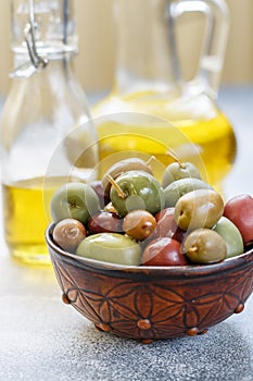 Mixed marinated olives green, black and purple in ceramic bowl and olive oil