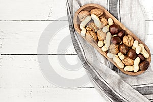 Mixed nuts in a bowl on a white wooden surface. Copy space