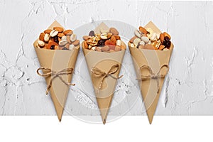 Mixed nuts and dried fruits in Retro Kraft Paper Cones on a light concrete background. Symbols of the Jewish holiday of Tu Bishvat