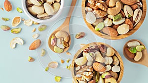 Mixed nuts healthy snack in wooden bowl on pastel blue background, top view