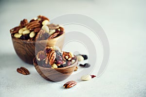 Mixed nuts and raisins in wooden bowl. Healthy food and snack. Walnut, pistachios, almonds, hazelnuts, cashews, raisins