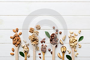mixed nuts in white wooden spoon. Mix of various nuts on colored background. pistachios, cashews, walnuts, hazelnuts