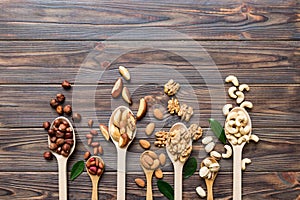 mixed nuts in white wooden spoon. Mix of various nuts on colored background. pistachios, cashews, walnuts, hazelnuts