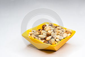 Mixed nuts in yellow bowl isolated