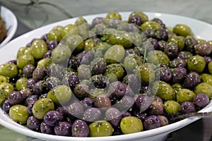 Mixed olives sprinkled with herbs in a white bowl